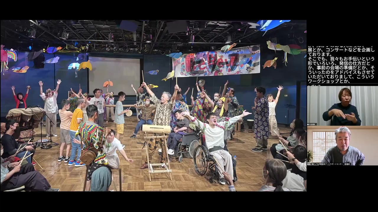 障害のある人もない人も一緒にステージに立つダンス・音楽イベントの様子。車椅子の参加者も含め、全員が手を上げてポーズを取っている。